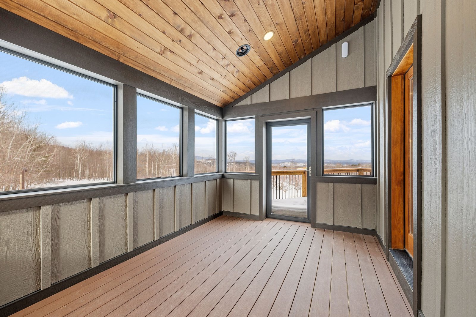 Sunroom addition with wood ceiling and wraparound windows