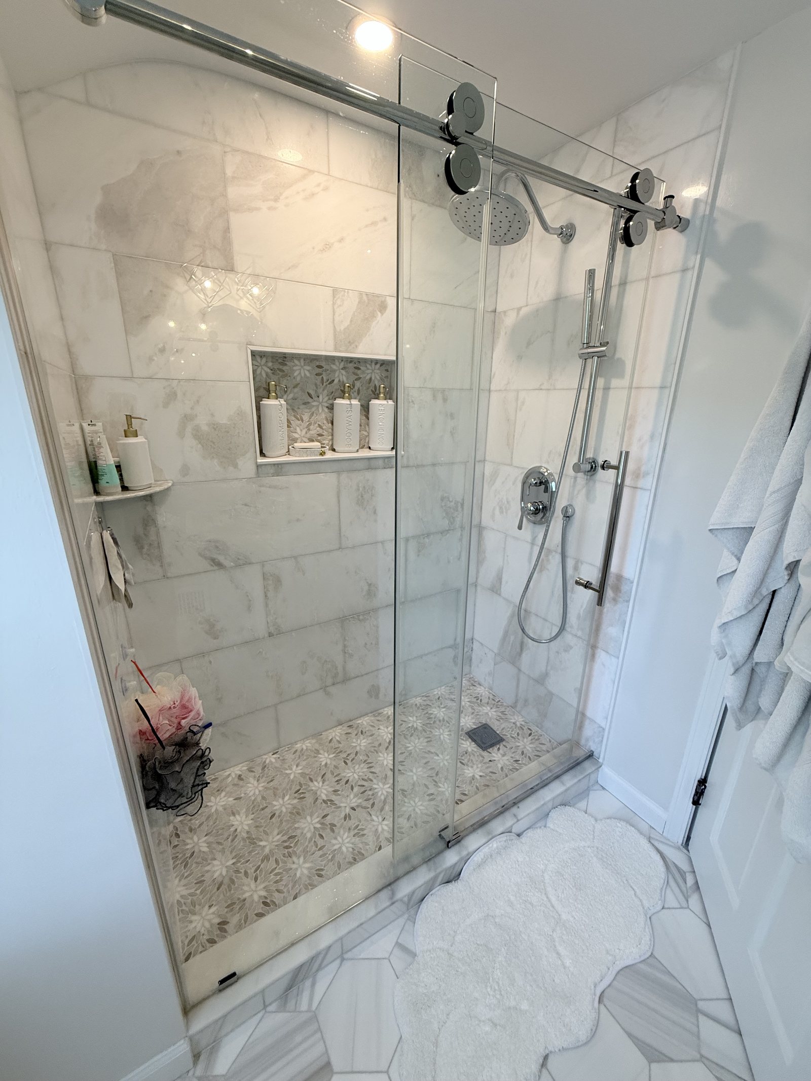 Walk-in shower finished in marble tile with a mosaic floor