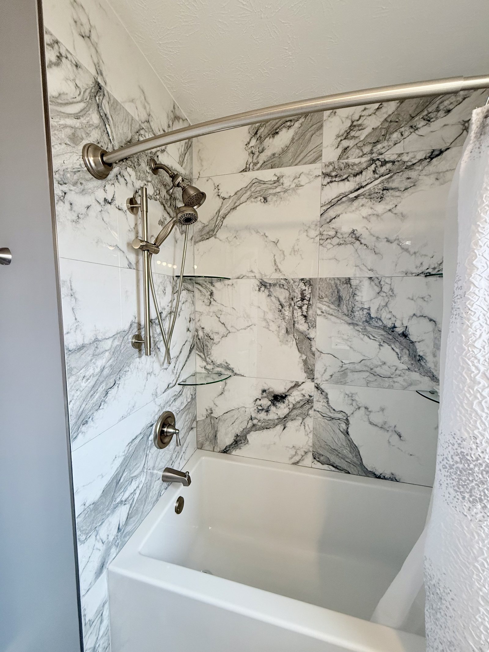 Bathtub surrounded by full-height marbled tile