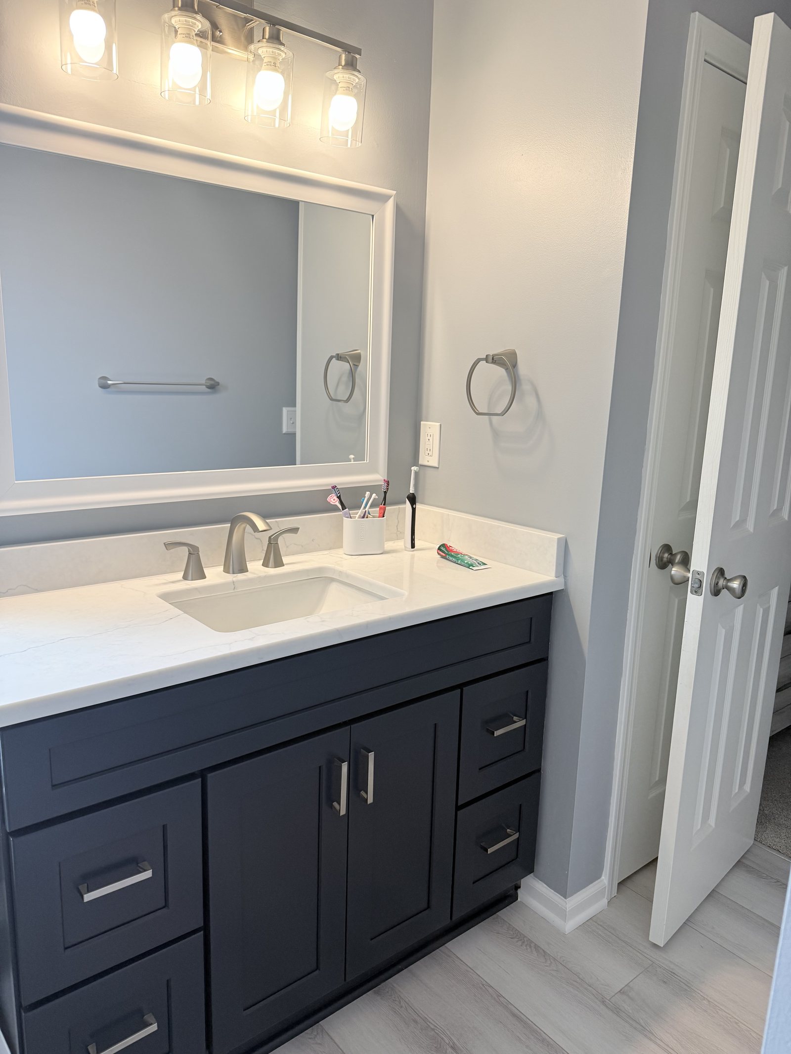 Navy bathroom vanity with a quartz top and framed mirror
