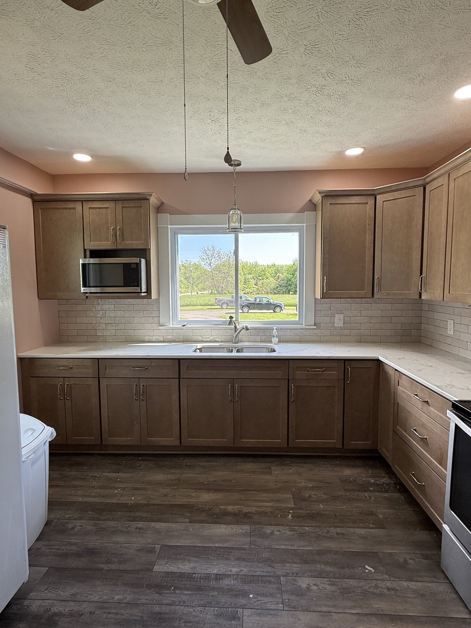 Renovated kitchen with shaker cabinetry, tile backsplash and quartz counters